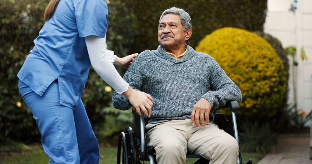 Older adult using a walker boards an accessible vehicle with assistance from a caregiver.